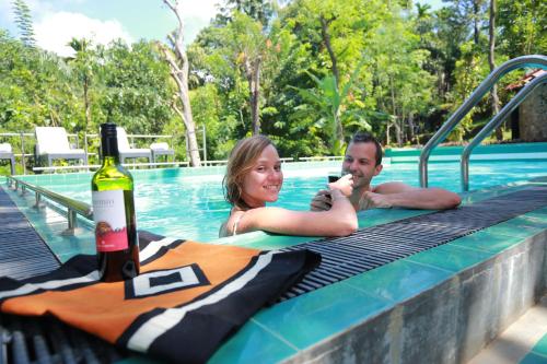a man and woman in a swimming pool with a bottle of wine at Ella Planters Bungalow in Ella