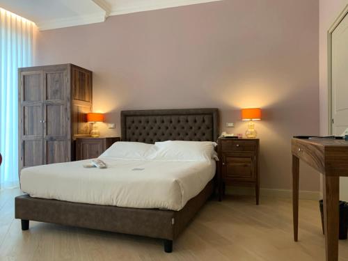 een slaapkamer met een bed en een bureau met 2 lampen bij Palazzo Dei Mercanti - Dimora & Spa in Ascoli Piceno
