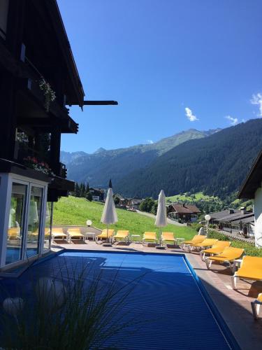 a swimming pool with lounge chairs and umbrellas at Apartment Hotel Pfeifer in Gaschurn