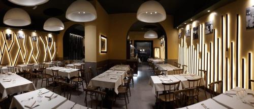 un comedor con mesas blancas, sillas y luces en CityLife Rome, en Roma