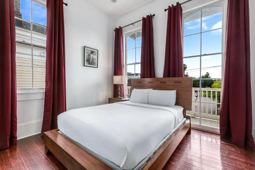 a bedroom with a large white bed and windows at Fabulous Cottages with City Views in New Orleans