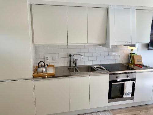 a kitchen with white cabinets and a sink at Easy Livin' Apartment Hotel in Växjö