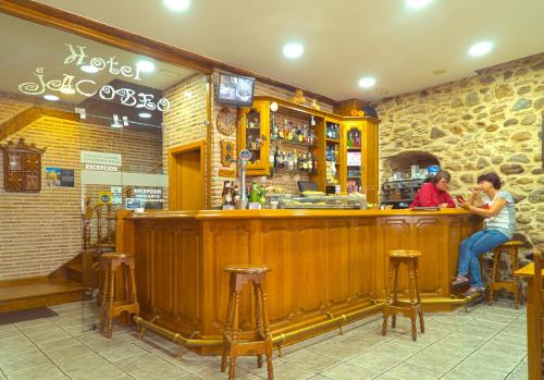 two people sitting at a bar in a restaurant at Hotel Jacobeo in Belorado