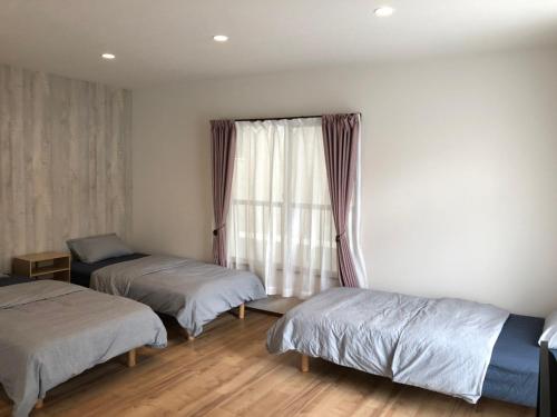 a bedroom with two beds and a window at Amami Weekly House Nico Nico Nazeko-ten in Amami