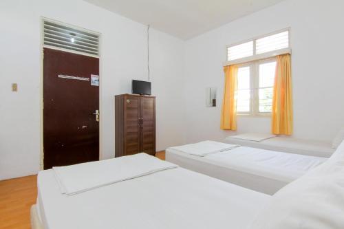 a white room with two beds and a window at Lestari Guesthouse in Padang