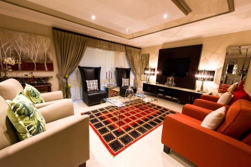 a living room with couches and a flat screen tv at Forest Manor Boutique Guesthouse in Durban