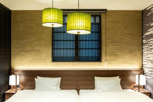 two beds in a room with two lights at La'gent Hotel Shinjuku Kabukicho in Tokyo