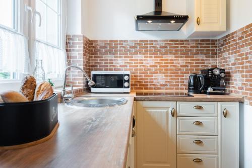 a kitchen with a sink and a brick wall at Lu Apartments in Oświęcim