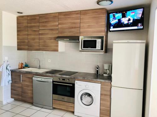 a kitchen with a white refrigerator and a microwave at Appartement 238 village LES SALICORNES in Arles