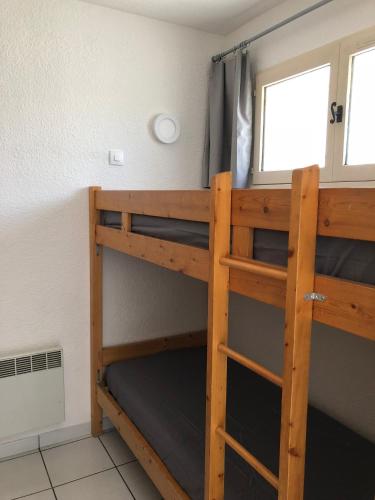deux lits superposés dans une chambre avec fenêtre dans l'établissement Appartement 238 village LES SALICORNES, à Arles