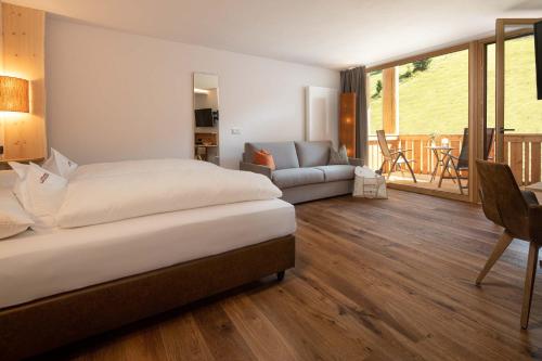 a bedroom with a bed and a living room at Moseralm Dolomiti Spa Resort in Nova Levante