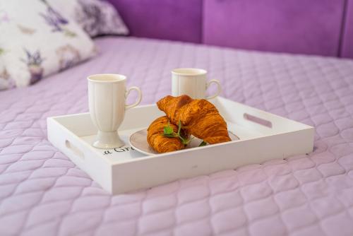 a tray with croissants and two cups on a bed at Lu Apartments in Oświęcim