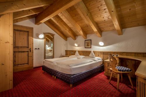 a bedroom with a large bed in a room with wooden ceilings at Residence Vila in Colfosco