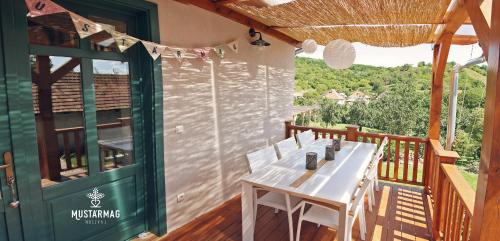 a wooden deck with a white table and chairs at Mustármag Vendégház in Noszvaj
