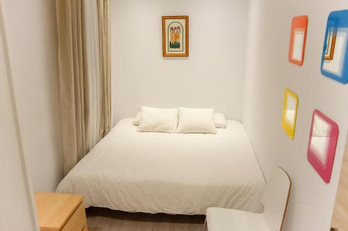 a small bedroom with a white bed and a chair at YOUR HOME - Sagrada Familia Apartment in Barcelona