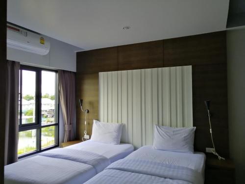 two beds in a hotel room with a window at Baan Bangkok 97 Hotel in Pathum Thani