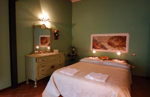 um quarto com uma cama, uma cómoda e um espelho em La Corte D'Elsa em Castelfiorentino