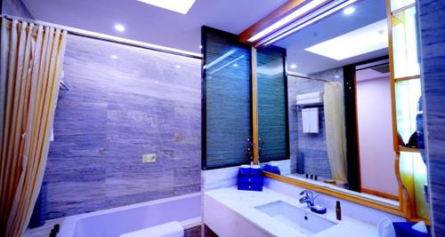 a bathroom with a tub and a sink and a mirror at Beijing Yun-zen Jinling Lotus Hotel in Beijing