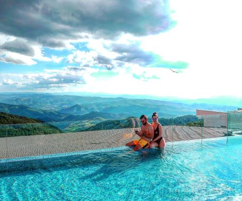 two people sitting in a swimming pool with a view at SM Apartments Kopaonik in Kopaonik