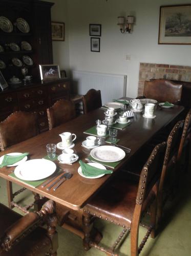 a wooden table with plates and dishes on it at Baron's Grange in Iden