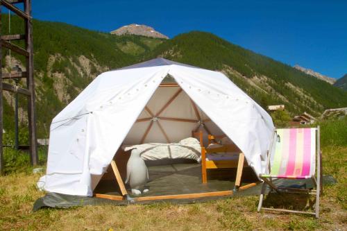 une tente avec un lit et deux chaises dans un champ dans l'établissement Les domes du Chalet Viso, à Arvieux