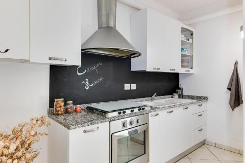 a kitchen with white cabinets and a stove top oven at Campus House in Forlì