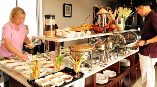 a man and a woman standing in front of a buffet at Anise Hotel & Spa Hanoi in Hanoi