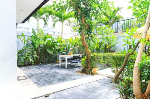 a patio with a table and chairs in a garden at Margarita Surf Hostel Canggu in Canggu