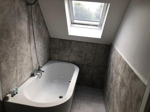 a bathroom with a bath tub and a window at Hamilton Arms Suites in Midhurst