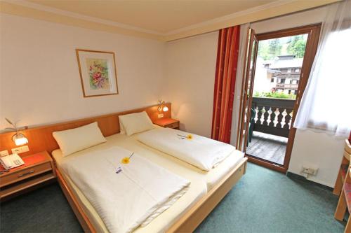 a bedroom with a large white bed with a window at Hotel Mitterer in Saalbach Hinterglemm