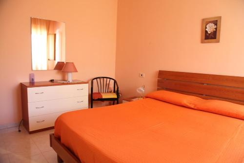 um quarto com uma cama laranja e uma cómoda em B&B La Villetta em Benevento