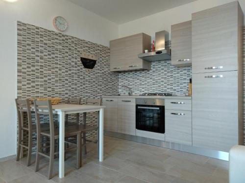 cocina con armarios blancos, mesa y sillas en Via Mediterraneo 39 Casa vacanze en Petacciato