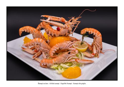 a plate of food with shrimp and lettuce and lemons at Hotel Krona Domžale in Domžale