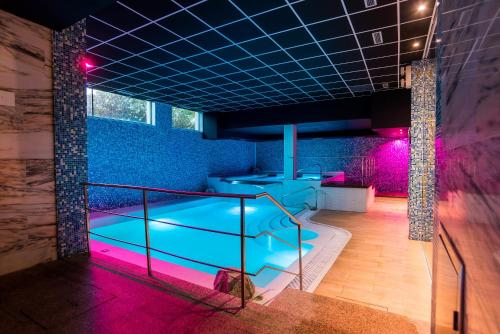 una piscina en una habitación con luces moradas en Hotel Spa Villa Pasiega, en Hoznayo