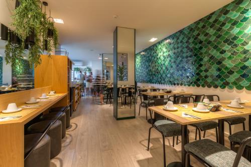 a restaurant with wooden tables and green walls at Hotel Spot Family Suites in Porto