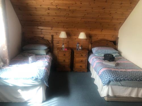 two twin beds in a room with wooden walls at 12 Tullybay Drumcrow east with WIFI in Enniskillen