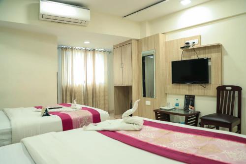 una camera d'albergo con due letti e una televisione di Hotel Plaza Executive - near BKC a Mumbai