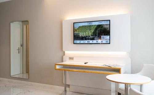 a tv on a wall with a table and a stool at Hotel Milano Castello in Milan