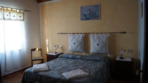 um quarto com uma cama e duas mesas de cabeceira e uma janela em Agriturismo Poggio San Pietro em Pitigliano