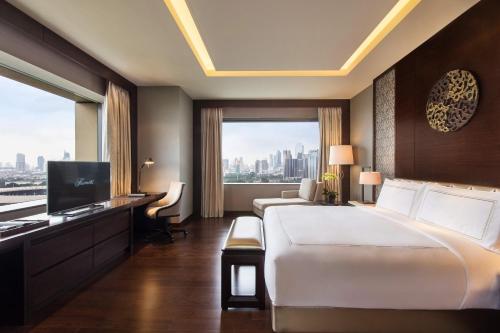 a hotel room with a large bed and a large window at Fairmont Jakarta in Jakarta
