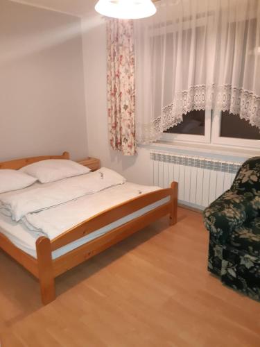 a bedroom with a bed and a chair and a window at Pokoje Gościnne Skalny Agroturystyka in Żabnica
