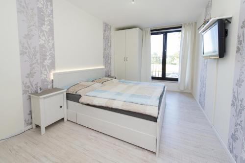 a white bedroom with a bed and a television at Rhinkieker Rees in Rees