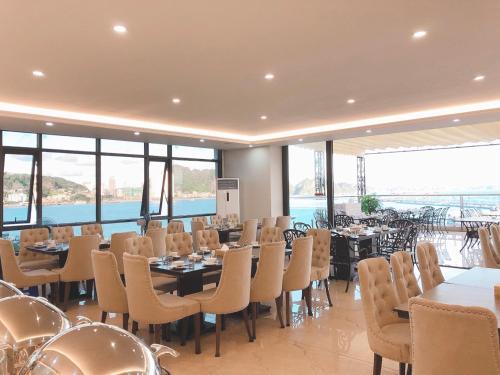 a restaurant with tables and chairs and a view of the water at Vincent Halong Hotel in Ha Long