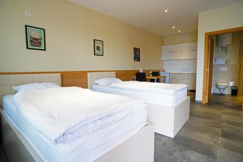 two twin beds in a room with a bathroom at Nava Motel & Storage in Wiener Neustadt