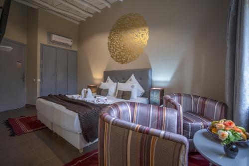 a hotel room with a bed and two chairs at Taj Atlas Wellness Boutique Hôtel & Spa in Amizmiz