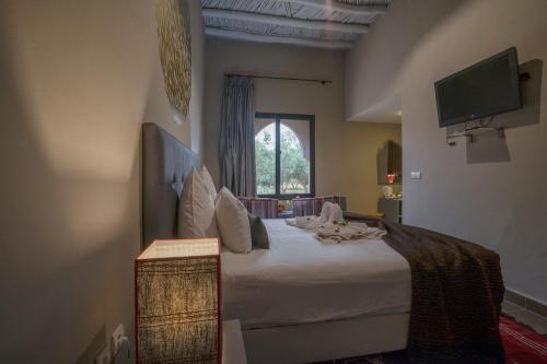 a bedroom with a bed with a tv and a window at Taj Atlas Wellness Boutique Hôtel & Spa in Amizmiz