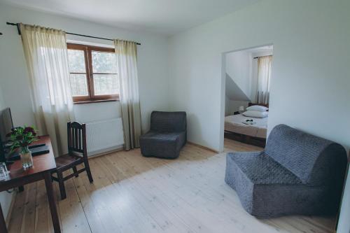 ein Wohnzimmer mit einem Stuhl, einem Schreibtisch und einem Bett in der Unterkunft Dwór Klembów in Klembów Kościelny