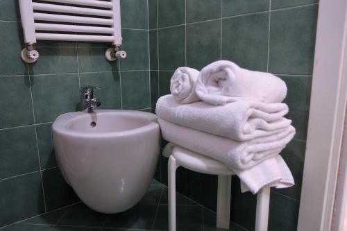 a bathroom with towels and a sink and a toilet at Albergo Fiorita in Bardolino