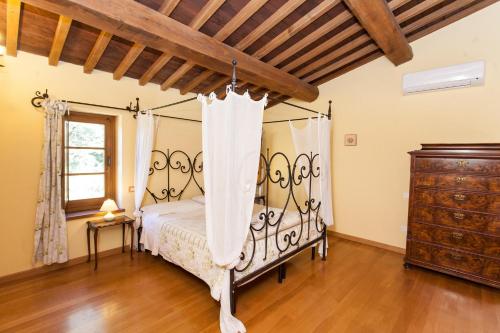a bedroom with a canopy bed and a wooden floor at Podere Caldaruccio La Pineta in Bosco
