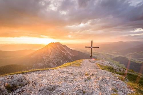 a cross on top of a mountain at sunset at Die Frida by Da Alois - Alpine Premium Apartments in Gröbming